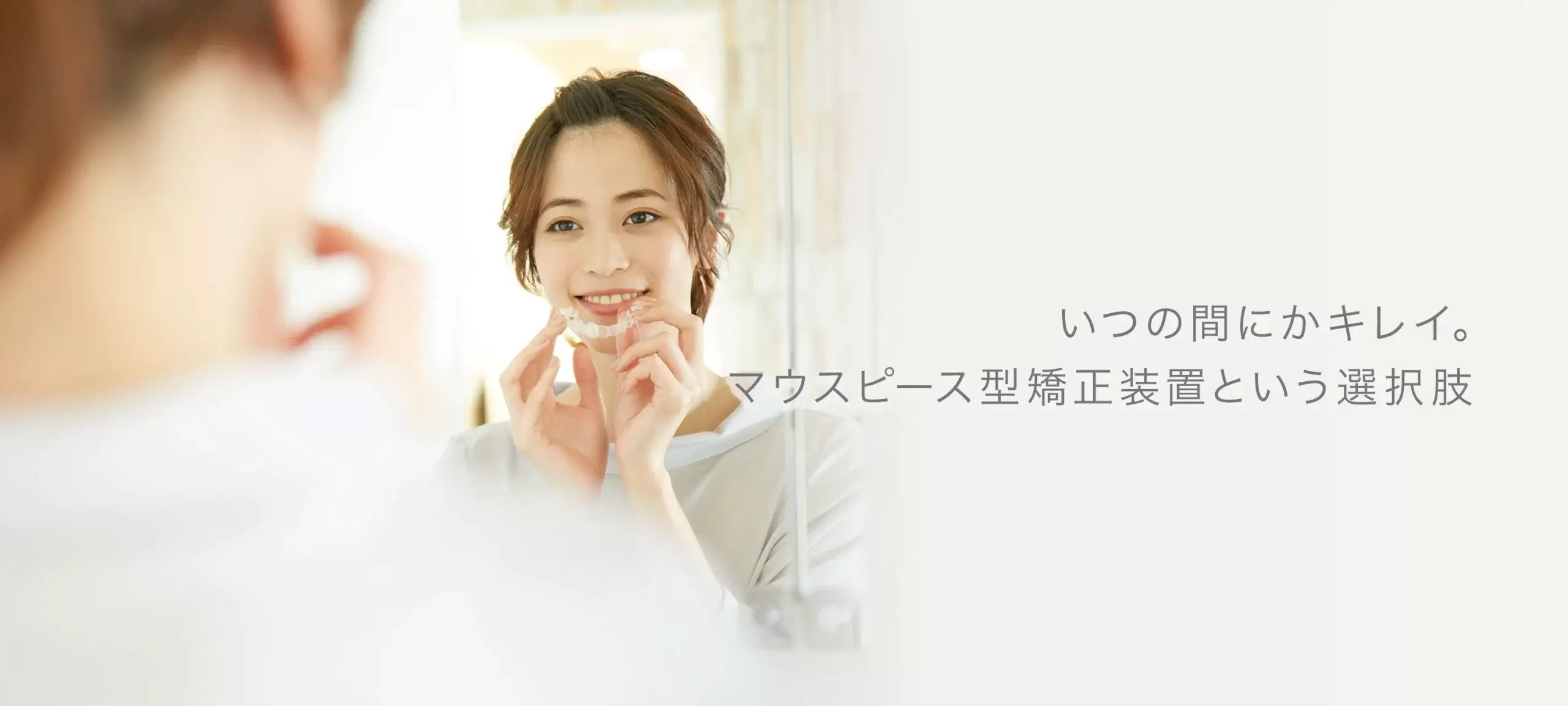 マウスピース型矯正装置イメージ（女性がマウスピース型矯正装置を口元に持っていっている）